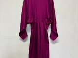 une robe violette suspendue à un cintre devant un mur blanc