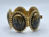 a close up of a gold bracelet with black stones on it