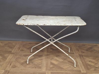 an old white iron table with a wooden top on a parquet floor