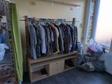 a rack of clothes in the corner of a room next to a window