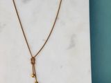 un collier en or orné d'une clochette, posé sur une dalle de marbre