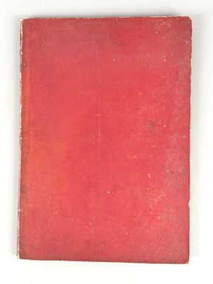 un vieux livre rouge posé sur une table blanche