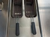 two deep fryers sitting on top of a stainless steel counter