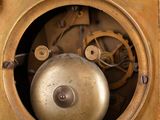 a gold clock with a bell inside of it