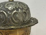 un plat ancien en argent avec un couvercle bombé, posé sur une table en bois