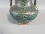 a green vase sitting on a table with a white background