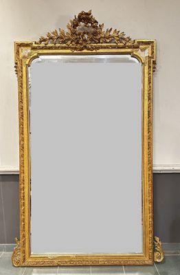 un miroir au cadre doré ouvragé posé sur un sol carrelé dans une pièce