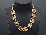 a gold necklace with blue and white beads on a mannequin