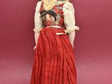 a doll of a woman wearing a red dress and a hat