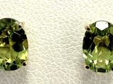 a pair of earrings with green stones sitting on top of a white surface