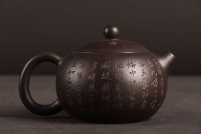 une théière marron posée sur une table, sur fond noir