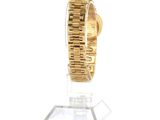 a gold watch on a clear stand on a white surface