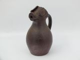 an old brown jug sitting on top of a white surface