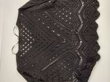 the top of a black knitted sweater laying on top of a white table