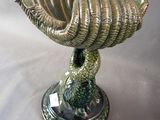 a green vase with a bird on it on a table