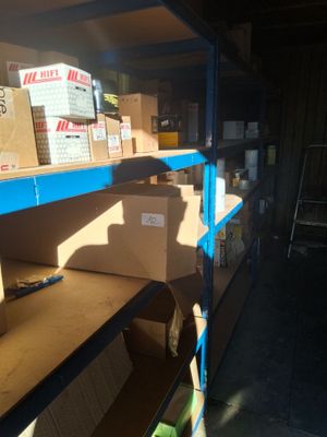 boxes are stacked on a shelf in a warehouse with a ladder in the background