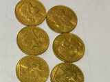 six gold coins sitting on top of each other on a white surface