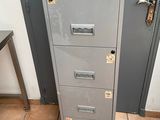 a metal filing cabinet in the corner of a room