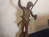 a bronze statue of a man holding a bird and a sword