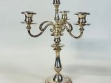 a silver candelier with three candles on a white background