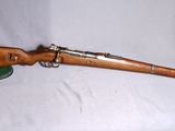 un fusil sur fond blanc, avec un chapeau posé dessus