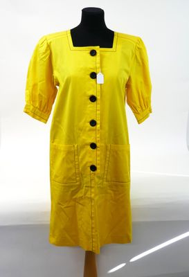 the dress is yellow and has black buttons on it