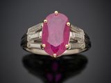 une bague ovale sertie d'un rubis et de diamants en taille baguette sur un fond noir