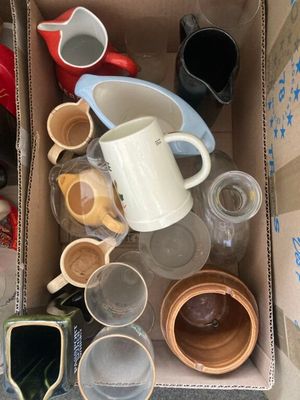 une boîte en carton remplie de tasses et de soucoupes, posée par terre