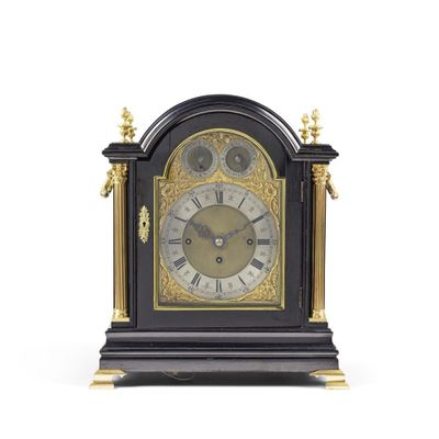 une horloge noire et or posée sur une surface blanche
