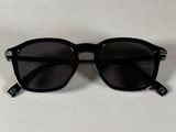 une paire de lunettes de soleil noires posée sur une table blanche