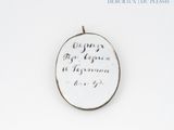 a picture of a silver pendant with writing on it