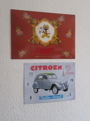 deux affiches accrochées au mur, au-dessus d'une voiture et d'une horloge