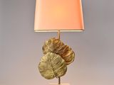 a gold leaf lamp with a pink shade on a white base