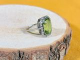 un gros plan d'une bague ornée d'une pierre verte posée sur un morceau de bois