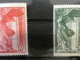 Deux timbres de couleurs différentes sont exposés dans une vitrine.
