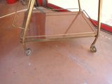 a gold bar cart on the floor in front of a red wall