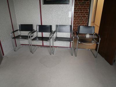 trois chaises dans une pièce où une télévision est accrochée au mur