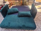 a green couch with pillows on it on a brick patio