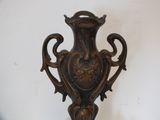 a bronze vase on a stand on a white wall