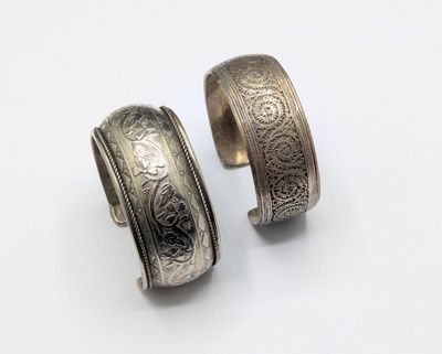 two silver rings with engraved designs on them on a white surface