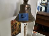 a bell hanging on the wall with a blue tag on it