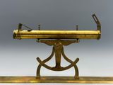 un télescope ancien en laiton posé sur un trépied, sur fond gris