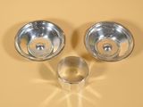 deux bols en argent et une coupe en argent posés sur un fond jaune