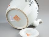 a white tea pot with a lid and a spoon on a table