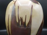 un vase marron et blanc posé sur une surface noire