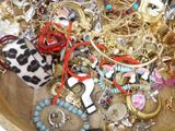 a wooden bowl filled with lots of assorted jewelry