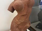 sculpture of a female torso on display in a glass case