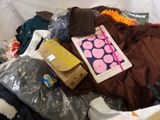 a pile of clothes and a book on a bed