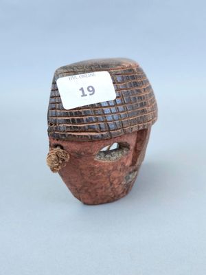 un petit masque en bois muni d'une étiquette