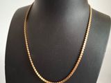 a gold chain necklace on a mannequin neck